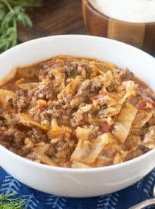 White bowl of stuffed cabbage soup with ground beef, tomato, and rice.