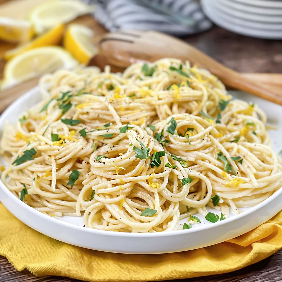 White plate with lemon pasta with fresh herbs.