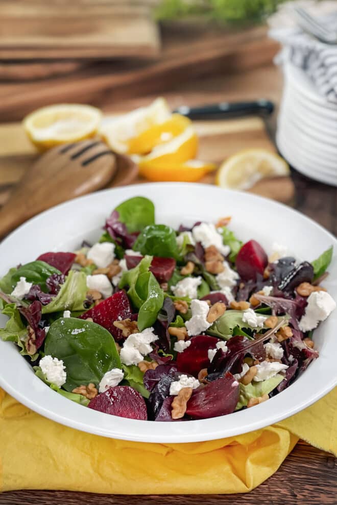 White bowl of salad with roasted beets and goat cheese.