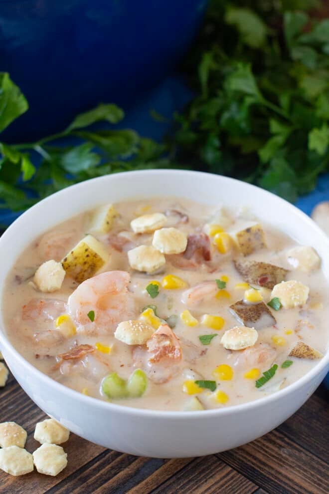 White bowl of shrimp chowder with potatoes and corn.