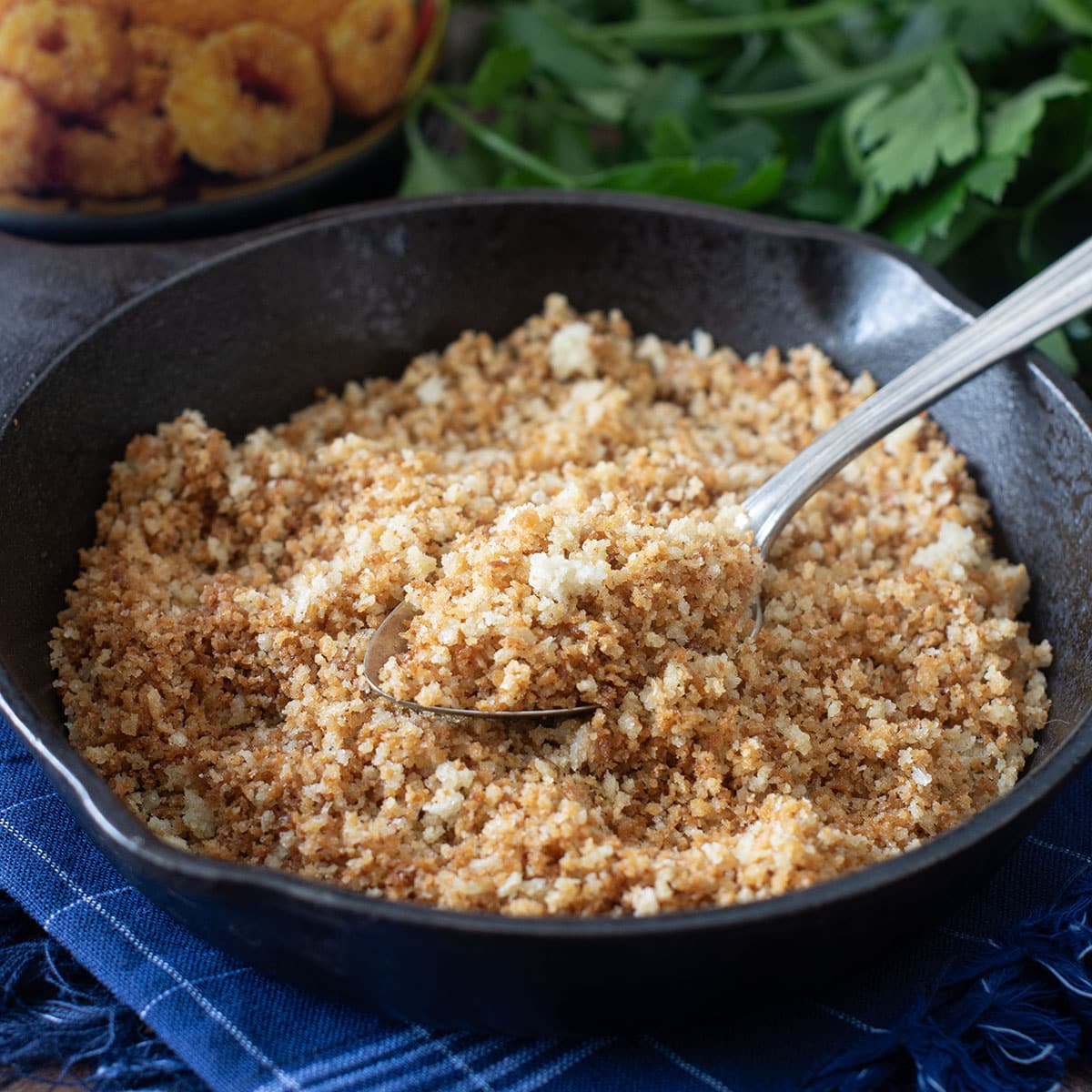 Small cast iron skillet with toasted panko breadcrumbs and spoon.