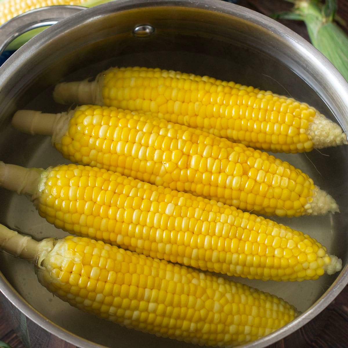 Four ears of corn in a large pot of water.