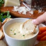 White bowl of parmesan cream cheese dip with cracker.