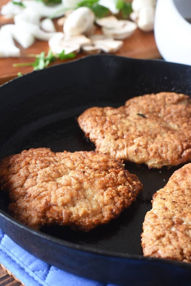 Cooked pork steaks in a cast iron pan.