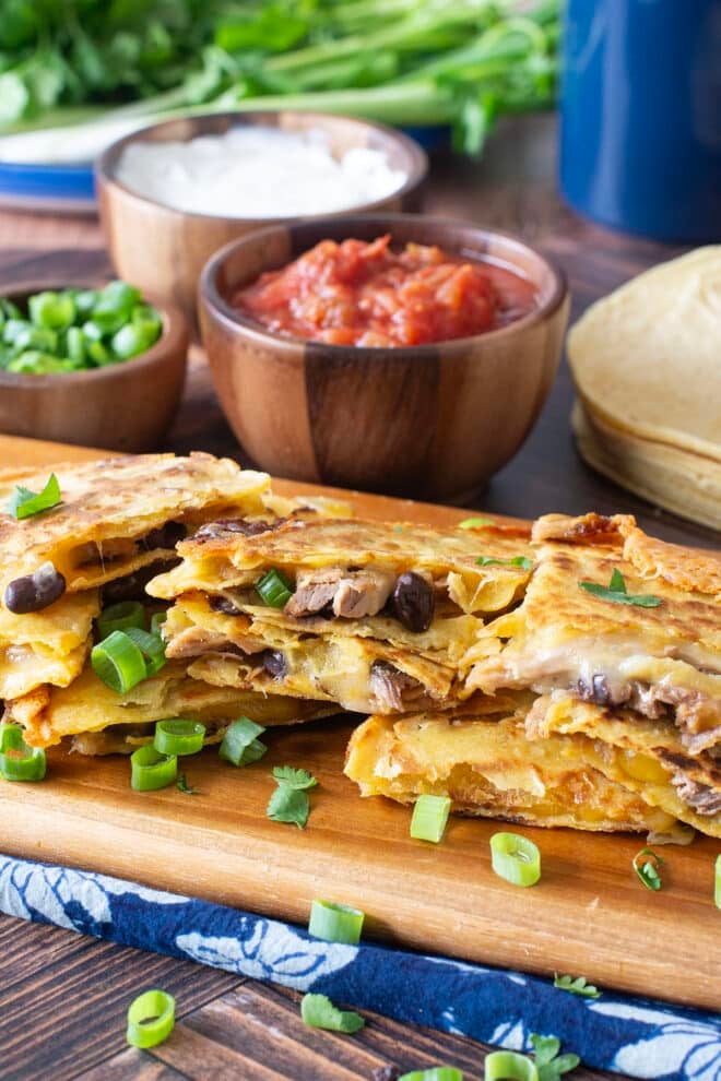 Slices of corn tortilla quesadillas with meat, black beans, and melty cheese.