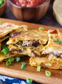 Slices of corn tortilla quesadillas with meat, black beans, and melty cheese.